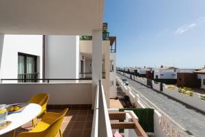 a balcony with yellow chairs and tables on a building at HomeForGuest Apartamento en residencia de lujo con terraza y piscina in La Guirra
