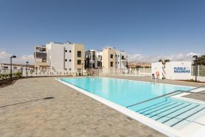 a large swimming pool with buildings in the background at HomeForGuest Apartamento en residencia de lujo con terraza y piscina in La Guirra