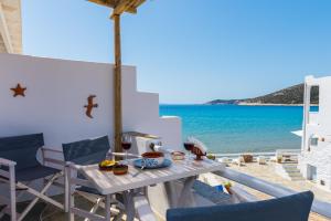 una mesa y sillas en un balcón con vistas al océano en Ammos Sifnos Village, en Platis Yialos Sifnos
