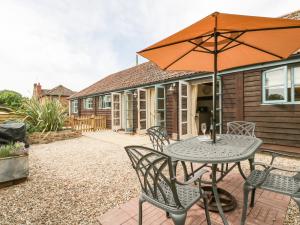 a patio with a table and chairs and an umbrella at Tom's Barn in Yeovil