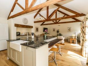 eine Küche mit einer großen Insel in einem Zimmer mit Holzbalken in der Unterkunft Tom's Barn in Yeovil