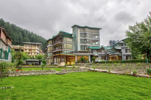 a large building with a green lawn in front of it at Woodrock Luxury Botique Hotel in Manāli
