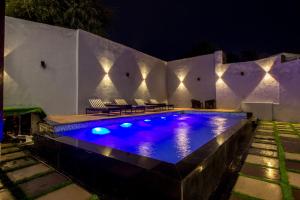 a swimming pool at night with chairs and lights at Woodrock Luxury Botique Hotel in Manāli