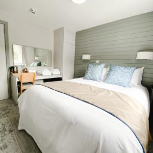a bedroom with a large white bed with blue pillows at South Sands Hotel in Weston-super-Mare