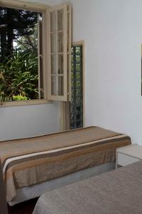 a bed sitting in a room with a window at Pousada Lagoa in Belo Horizonte