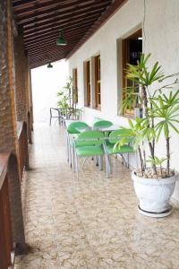 een patio met groene stoelen, tafels en planten bij Pousada Lagoa in Belo Horizonte