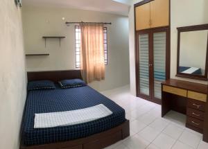 - une chambre avec un lit, une commode et un miroir dans l'établissement Awani Homestay, à Permatang Janggus