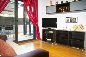 sala de estar con TV y cortinas rojas en Apartamento PR 39 terraza y piscina Tossa de Mar, en Tossa de Mar