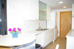 uma cozinha branca com um lavatório e uma mesa em Apartamento PR 39 terraza y piscina Tossa de Mar em Tossa de Mar