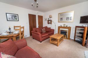 ein Wohnzimmer mit einem roten Sofa und einem Kamin in der Unterkunft Quaver Cottage in Keswick