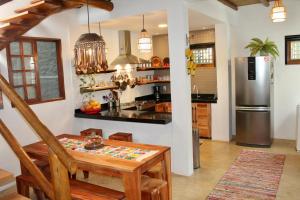a kitchen with a table and a stainless steel refrigerator at GREEN HOUSE ARRAIAL D'AJUDA in Arraial d'Ajuda