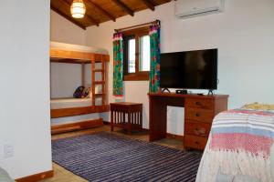 a bedroom with a bed and a flat screen tv at GREEN HOUSE ARRAIAL D'AJUDA in Arraial d'Ajuda