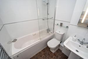 a bathroom with a toilet and a tub and a sink at Coledale in Keswick