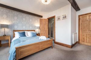 um quarto com uma cama com lençóis azuis e uma cómoda em madeira em Bridge House Apartment 2 em Keswick
