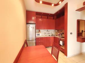 La cuisine est équipée de placards rouges, d'une table et d'un réfrigérateur. dans l'établissement Apartments Altea, à Rafailovici