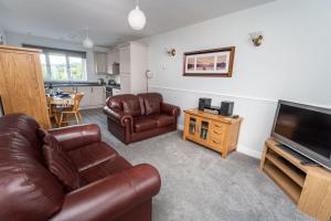 a living room with leather furniture and a flat screen tv at Alison's View in Keswick