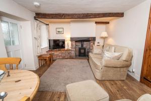 a living room with a couch and a fireplace at Jasmine Cottage in Portinscale