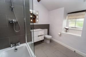 a bathroom with a tub and a toilet and a shower at Jasmine Cottage in Portinscale +14 photos