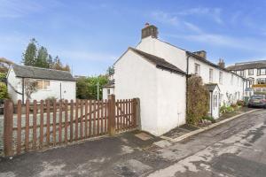 a white house with a wooden fence on a street at Jasmine Cottage in Portinscale