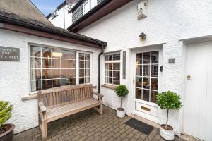 a wooden bench sitting outside of a white building at Daisy Cottage in Keswick