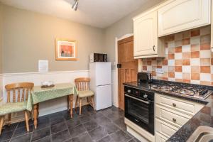 eine Küche mit einem Tisch und einem weißen Kühlschrank in der Unterkunft Rose Bank Cottage in Braithwaite