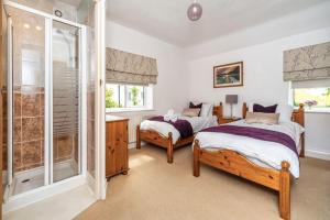 a bedroom with two beds and a shower at Rose Bank Cottage in Braithwaite