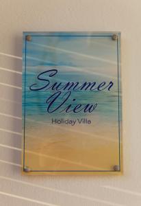 Una señal que lee el verano y cuelga de una pared. en Summer View en Skala