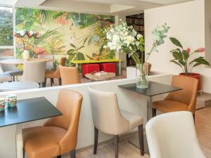a restaurant with tables and chairs and flowers on the wall at ibis Styles Beaulieu sur Mer in Beaulieu-sur-Mer