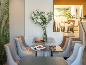 a dining room with a table and chairs and a vase of flowers at ibis Styles Beaulieu sur Mer in Beaulieu-sur-Mer