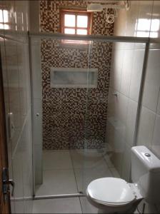 a bathroom with a glass shower with a toilet at Barbosa acomodações. Lencois-BA in Lençóis