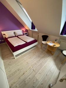 a attic bedroom with a bed and a table and a chair at Gästehaus Lavendel in Flensburg