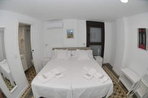 a bedroom with a white bed with white sheets and pillows at Horno de la Higuera Alojamiento in Tudela