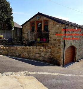 a stone house with a brick wall and a garage at Stone Eater in Marsden