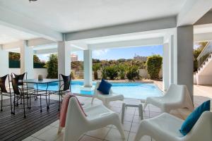 un patio con sillas blancas y una piscina en Villa Rosana, en Albufeira