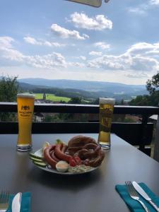 a plate of food on a table with two glasses of beer at Apartment Tälerblick in Böbrach