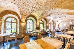 Aux Tanneries de Wiltz في Wiltz: مطعم بطاولات وكراسي وجدار من الطوب