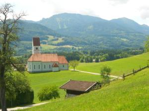 una chiesa bianca in un campo verde con una collina di Lenzenhof, Familie Christian und Stefanie Spitzl a Frasdorf