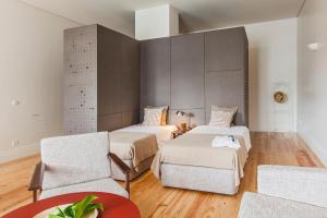 a room with two beds and a table and chairs at bnapartments Loftpuzzle in Porto