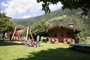 un jardín con parque infantil y una casa en Ledererhof, en Aschau