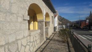 um edifício de pedra com arcos ao lado de uma rua em Casa Rural los Portalillos I em Navatalgordo