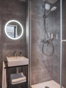 La salle de bains est pourvue d'une douche, d'un lavabo et d'un miroir. dans l'établissement Hôtel Piapia, à Paris
