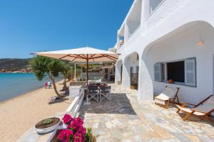 a patio with a table and an umbrella and the beach at Grandma's sifnos house in Platis Gialos