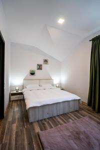 a bedroom with a large white bed and wooden floors at APARTAMENT CETATE VIEW in Râşnov