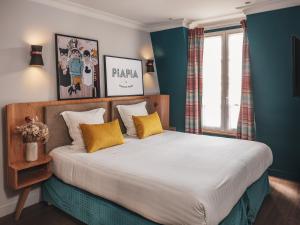 - une chambre avec un grand lit et des oreillers jaunes dans l'établissement Hôtel Piapia, à Paris