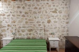 ein Schlafzimmer mit einem Bett mit einer grünen Decke und 2 Tischen in der Unterkunft Casa vacanze Krimisòs in Castellammare del Golfo