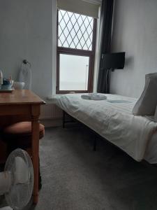 1 dormitorio con cama, escritorio y ventana en Craigwell, en Morecambe