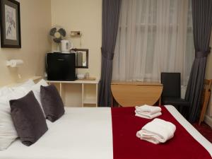 Una habitación de hotel con una cama con toallas. en Arran House Hotel en Londres