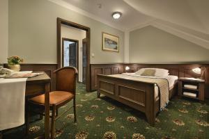 a bedroom with a bed and a table and a desk at Hotel Podhrad in Hluboká nad Vltavou