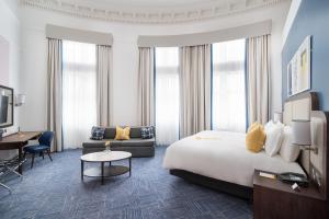 voco Grand Central - Glasgow, an IHG Hotel في غلاسكو: غرفة في الفندق مع سرير مزدوج كبير ومكتب