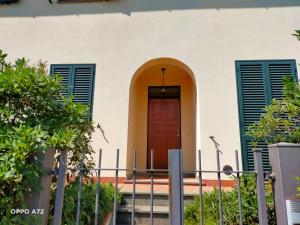 una casa con puerta roja y persianas verdes en L'OLIVO appartamento turistico en Lucignano